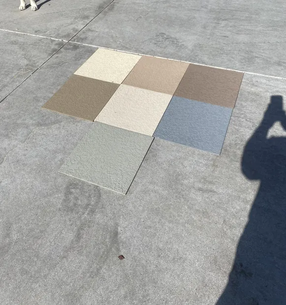 Five textured deck coating samples in cream, tan, gray and blue-gray set out on a walkway