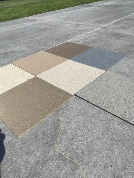 Textured deck coating samples laid out across a driveway next to existing concrete