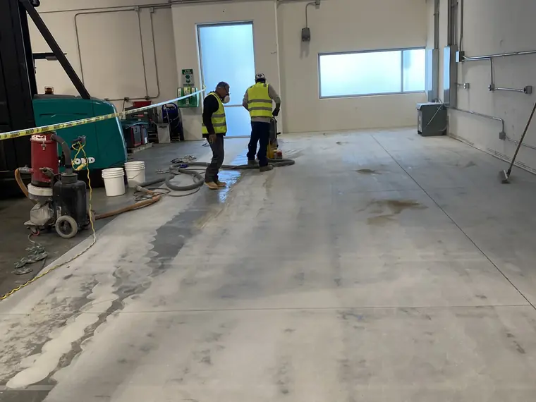 Crew and grinding equipment working across a warehouse slab during a coating removal