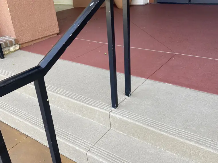 Resurfaced entry steps with a black handrail and a red bordered landing