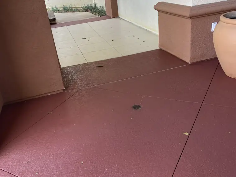 Cream and red resurfaced walkway running past a stucco column