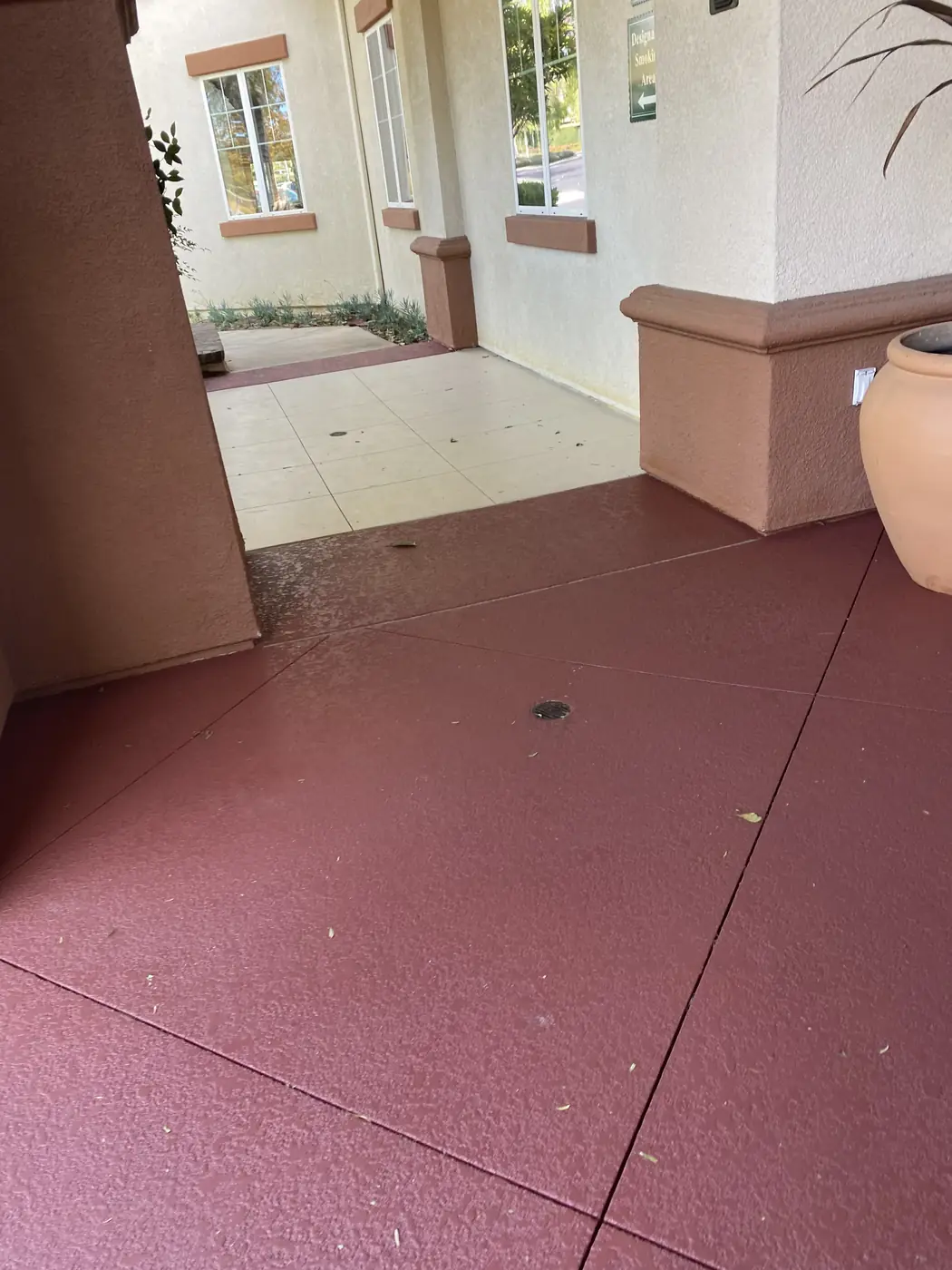 Cream and red resurfaced walkway running past a stucco column