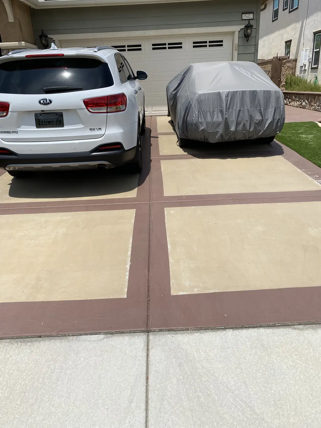 Resurfaced driveway in cream with brown banding and parked cars