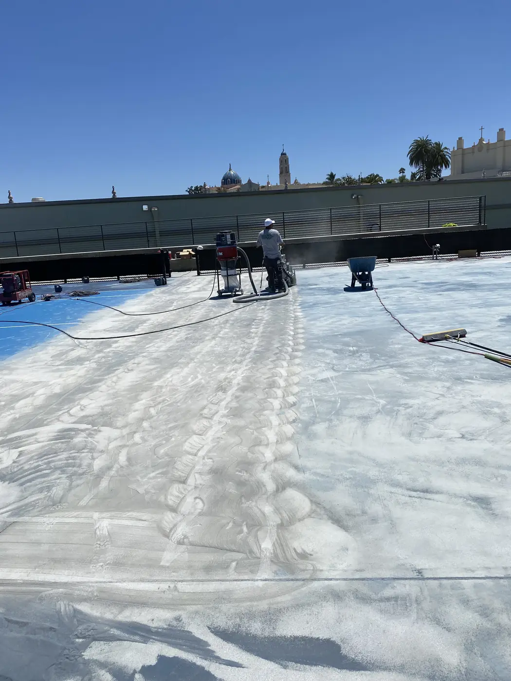 Court part-stripped, with grinding dust across the exposed concrete