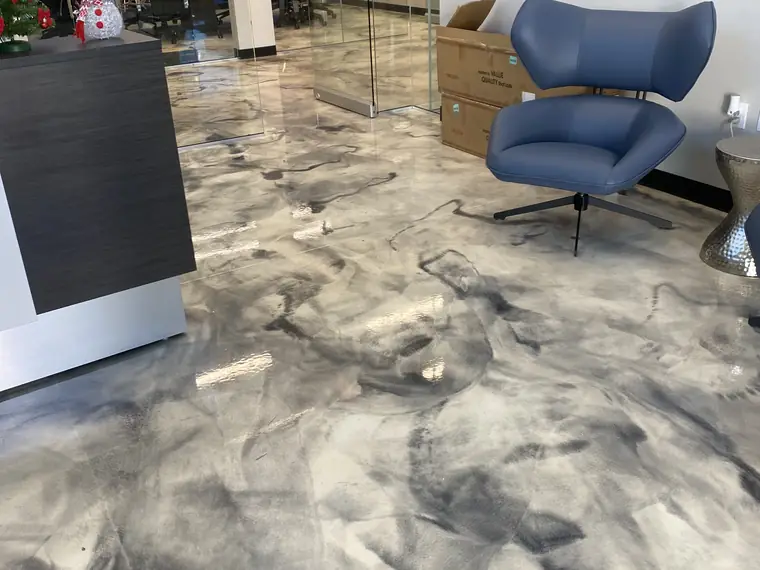 Marbled gray metallic epoxy floor in an office lounge with a blue armchair
