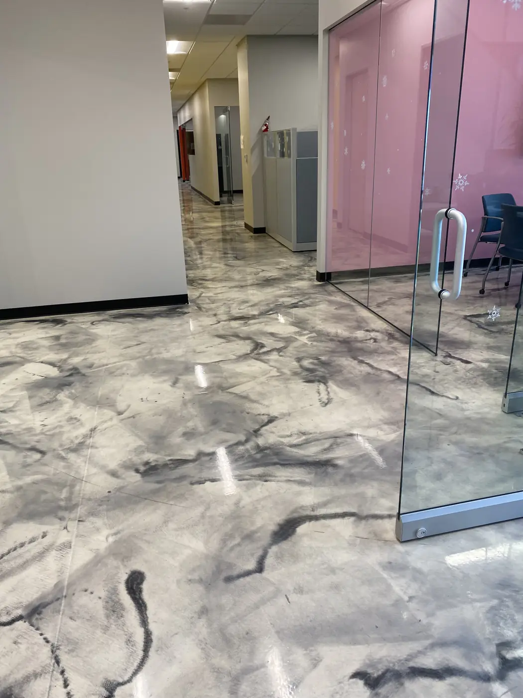 Gray and white metallic epoxy floor running down an office corridor past frosted glass