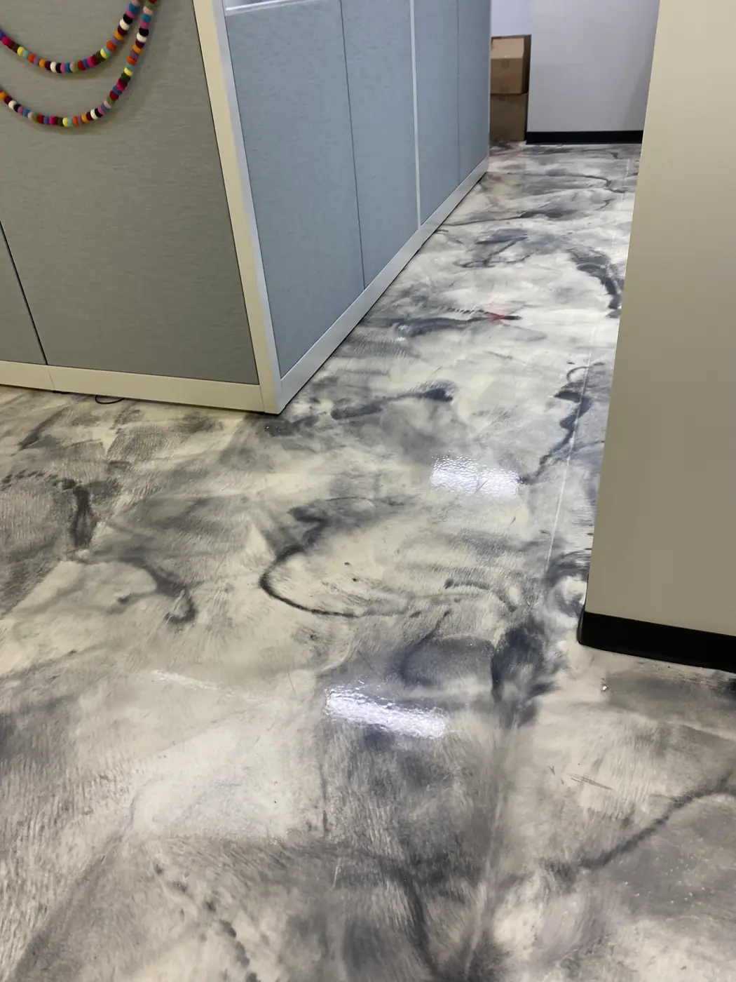 Swirled metallic epoxy floor running between office cubicle partitions