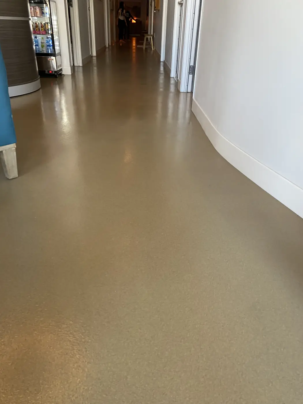 Bronze flake epoxy floor curving down a commercial hallway past a blue column