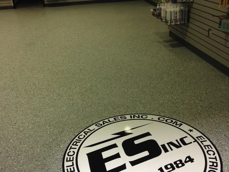 Retail store floor in olive flake epoxy with a circular company logo inlay