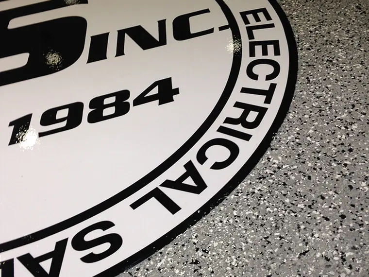 Company crest inlaid into speckled gray flake epoxy at floor level