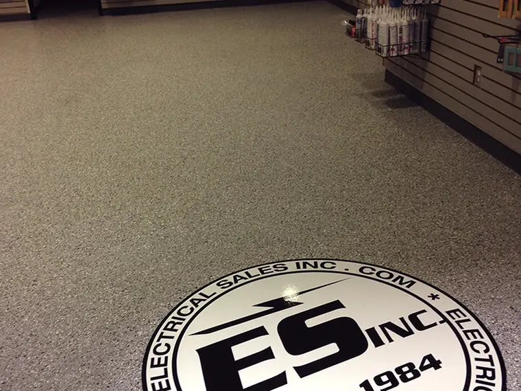 Retail sales floor in tan flake epoxy with a round logo inlay near the counter