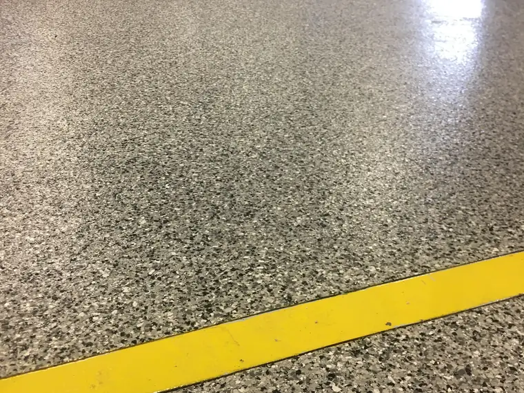 Gray flake epoxy floor with a yellow safety line running across it