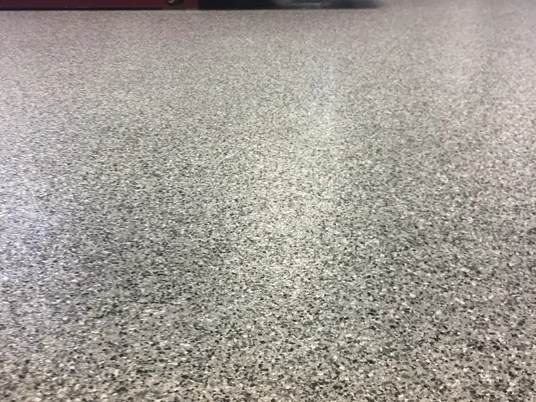 Gray flake epoxy floor beneath a wheel alignment rack in a service shop