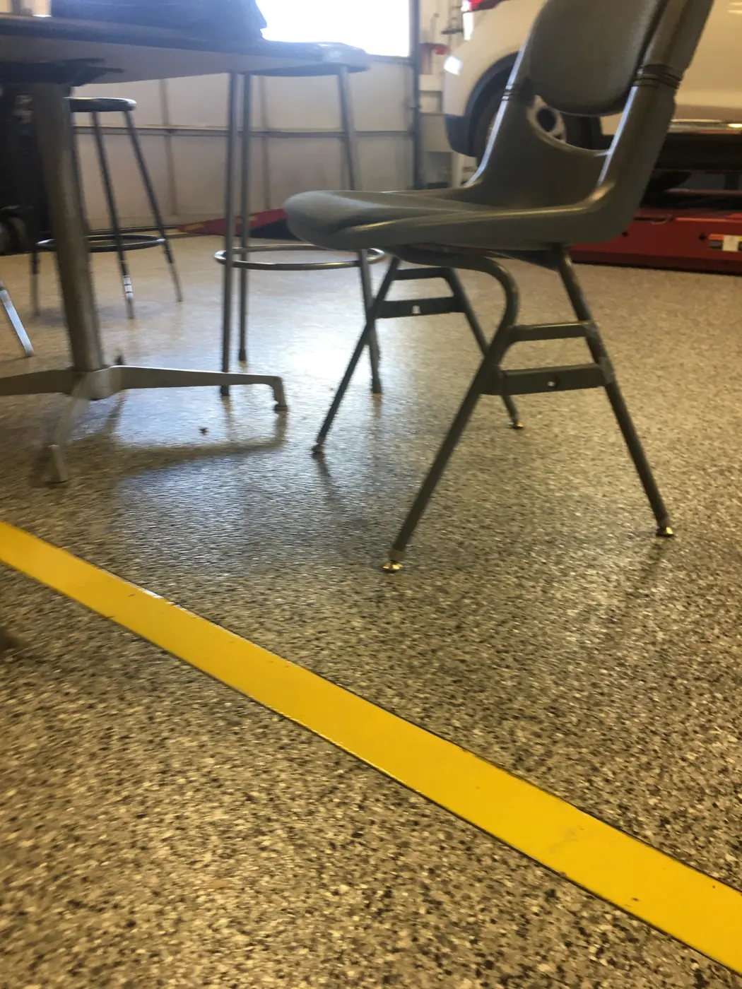 Olive flake epoxy shop floor with a yellow boundary line and a work chair