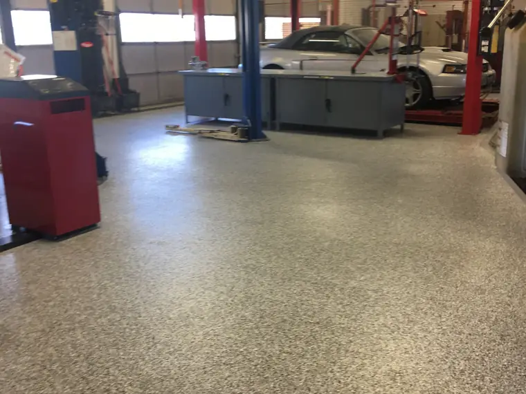 Tan flake epoxy floor running through a service shop past the vehicle lifts