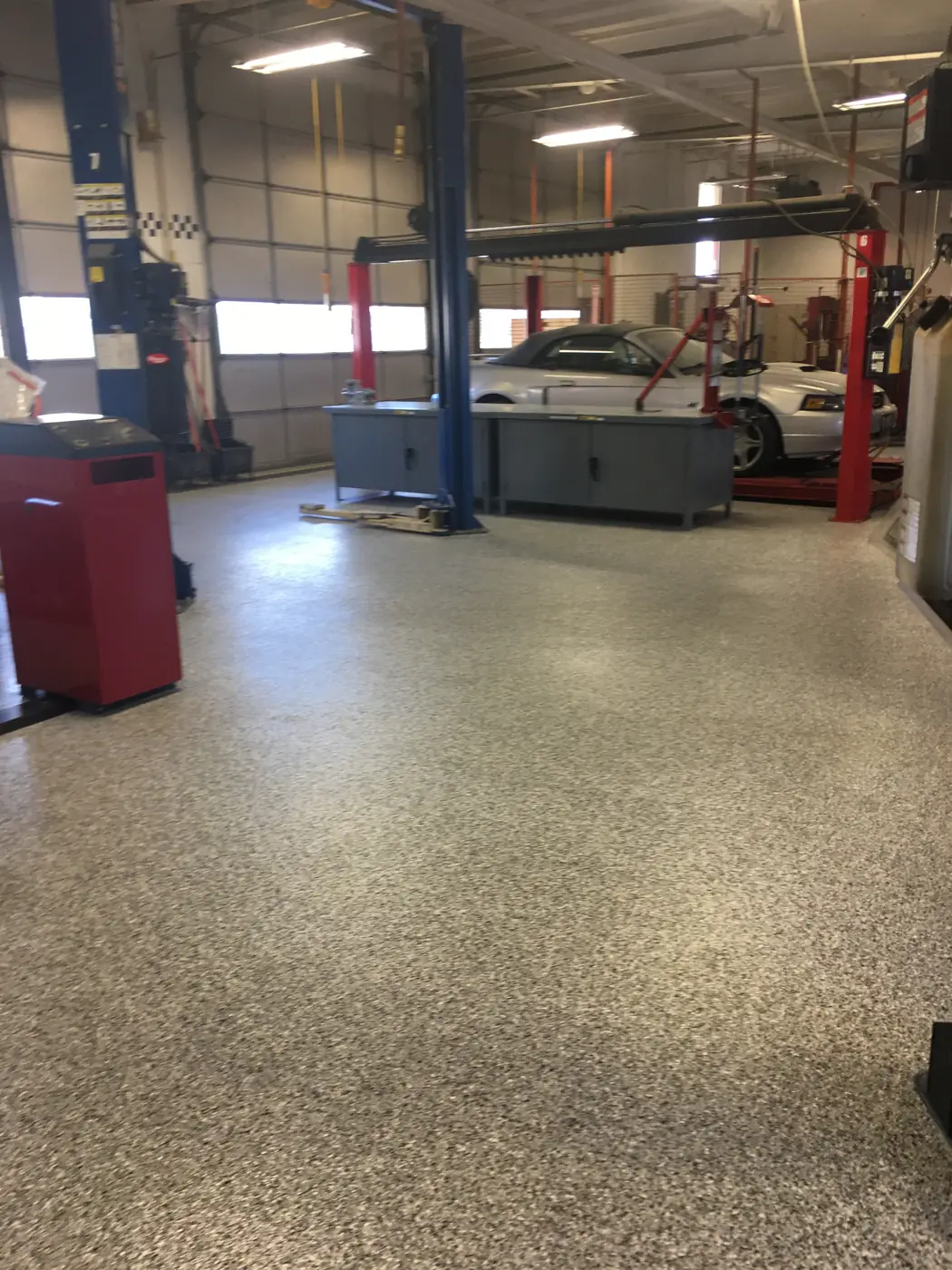 Tan flake epoxy floor running through a service shop past the vehicle lifts