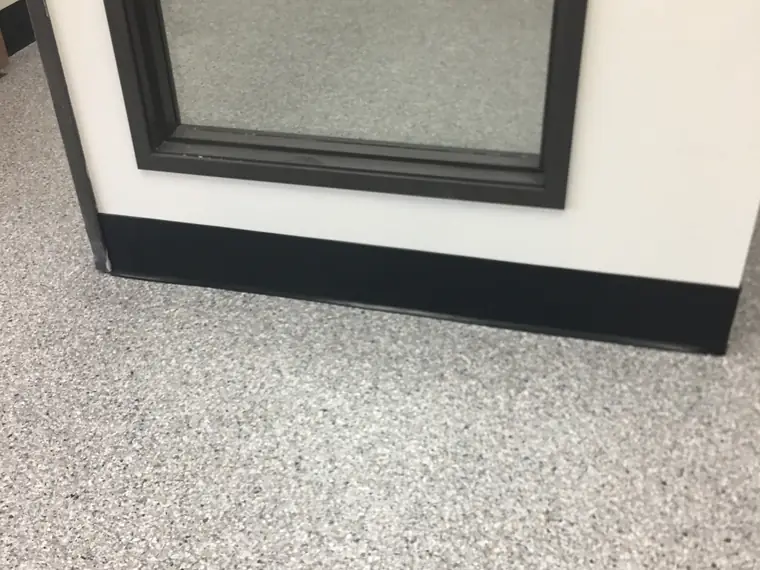 Gray flake epoxy floor meeting the base of a window display frame