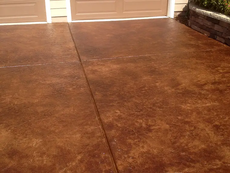 Rich brown stained driveway running up to a residential garage door
