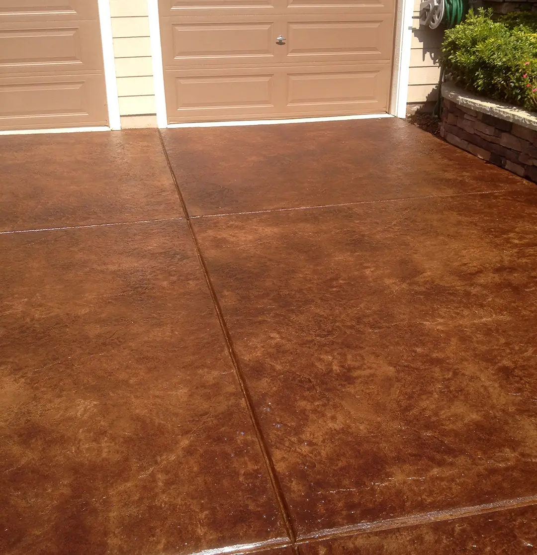 Rich brown stained driveway running up to a residential garage door