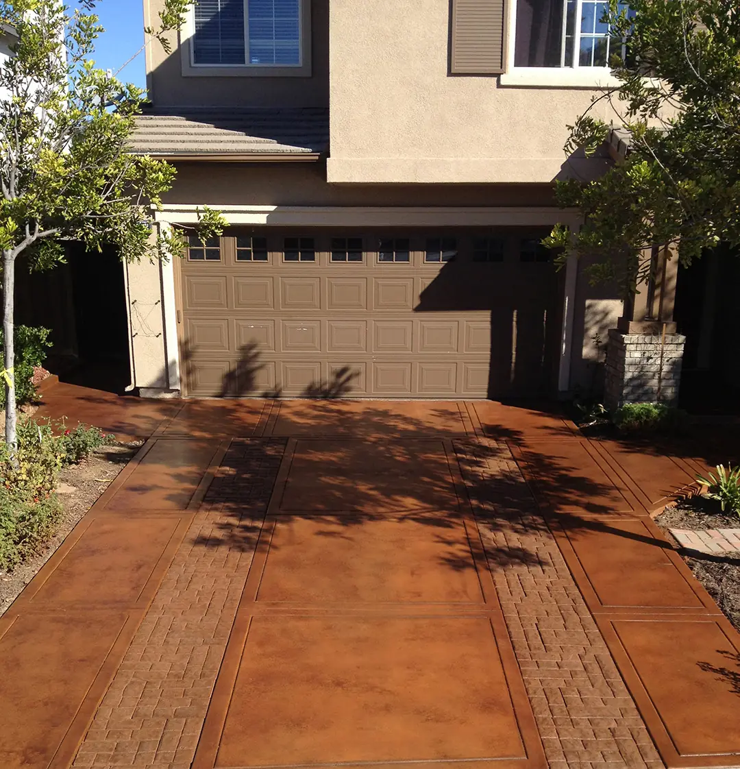 Rust stained driveway with a brick border in front of a two-story home
