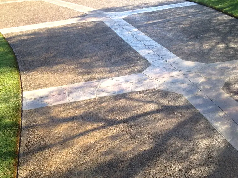 Stained driveway broken up with white banding leading to a garage