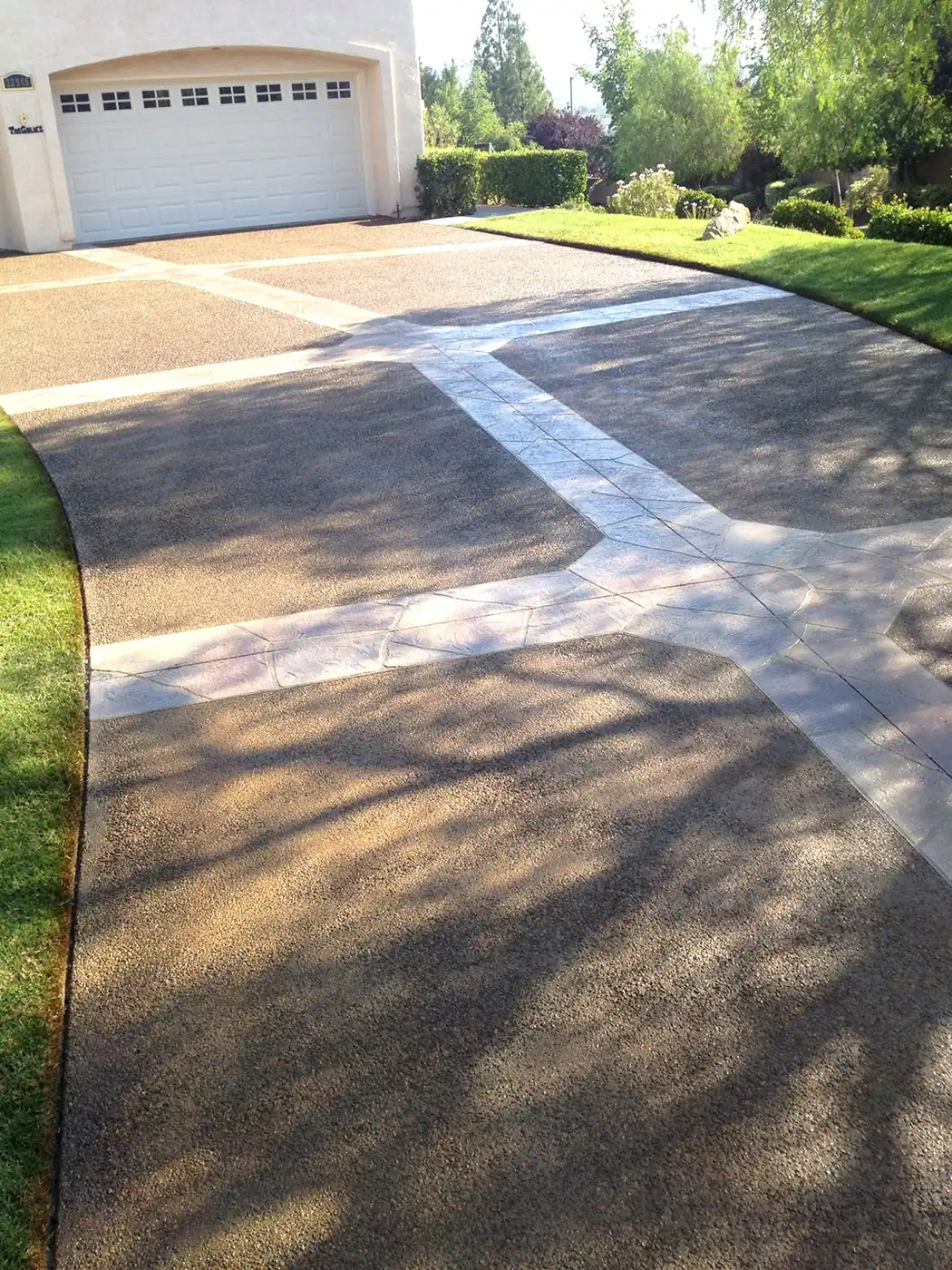 Stained driveway broken up with white banding leading to a garage