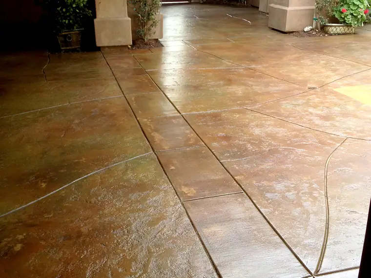 Stained entry patio scored in a tile pattern beside a stucco column