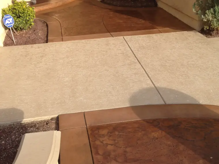 Stained front entry walkway in warm brown meeting a cream patio