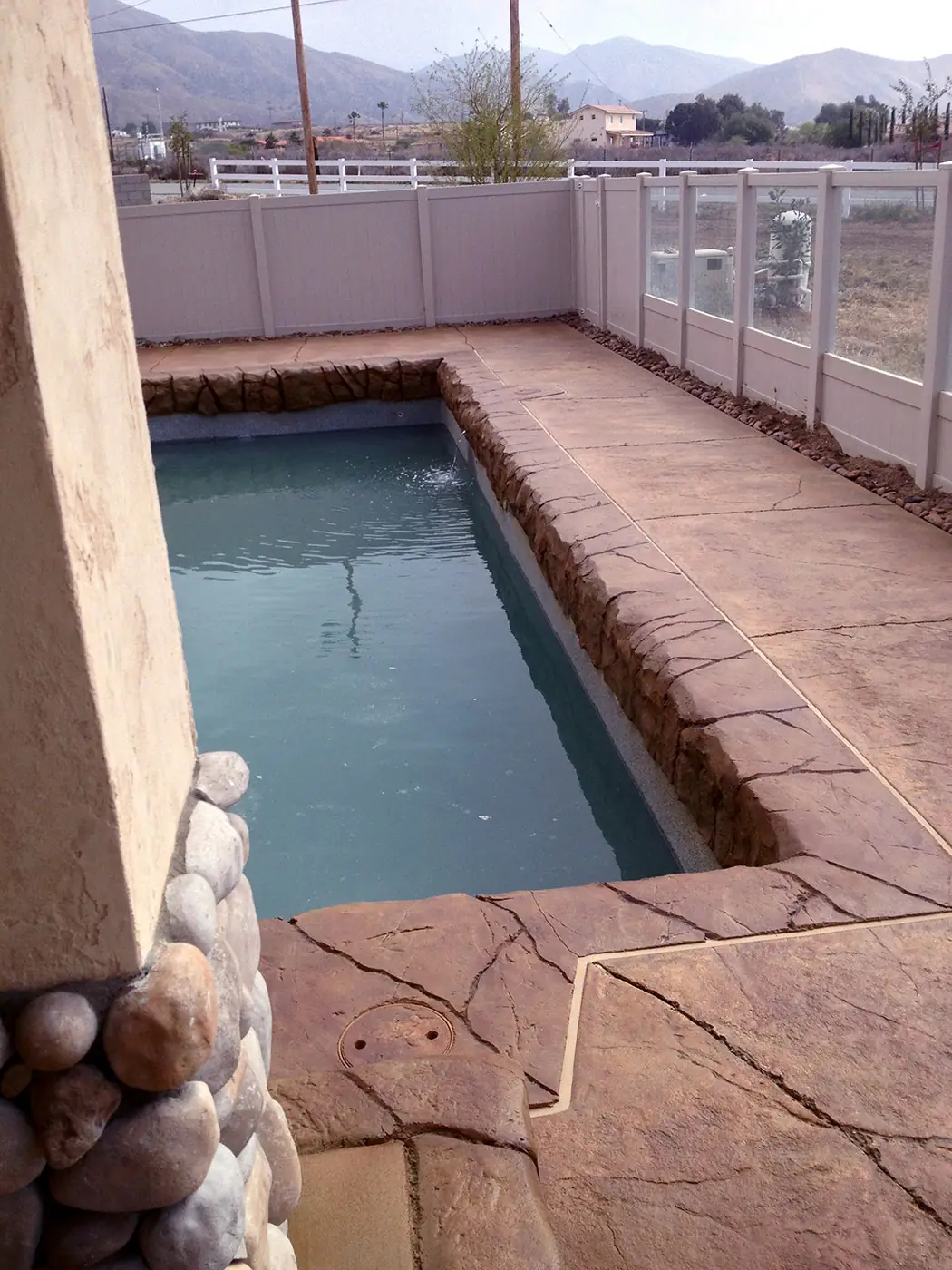 Pool deck stained and cut to a flagstone look around a rectangular pool
