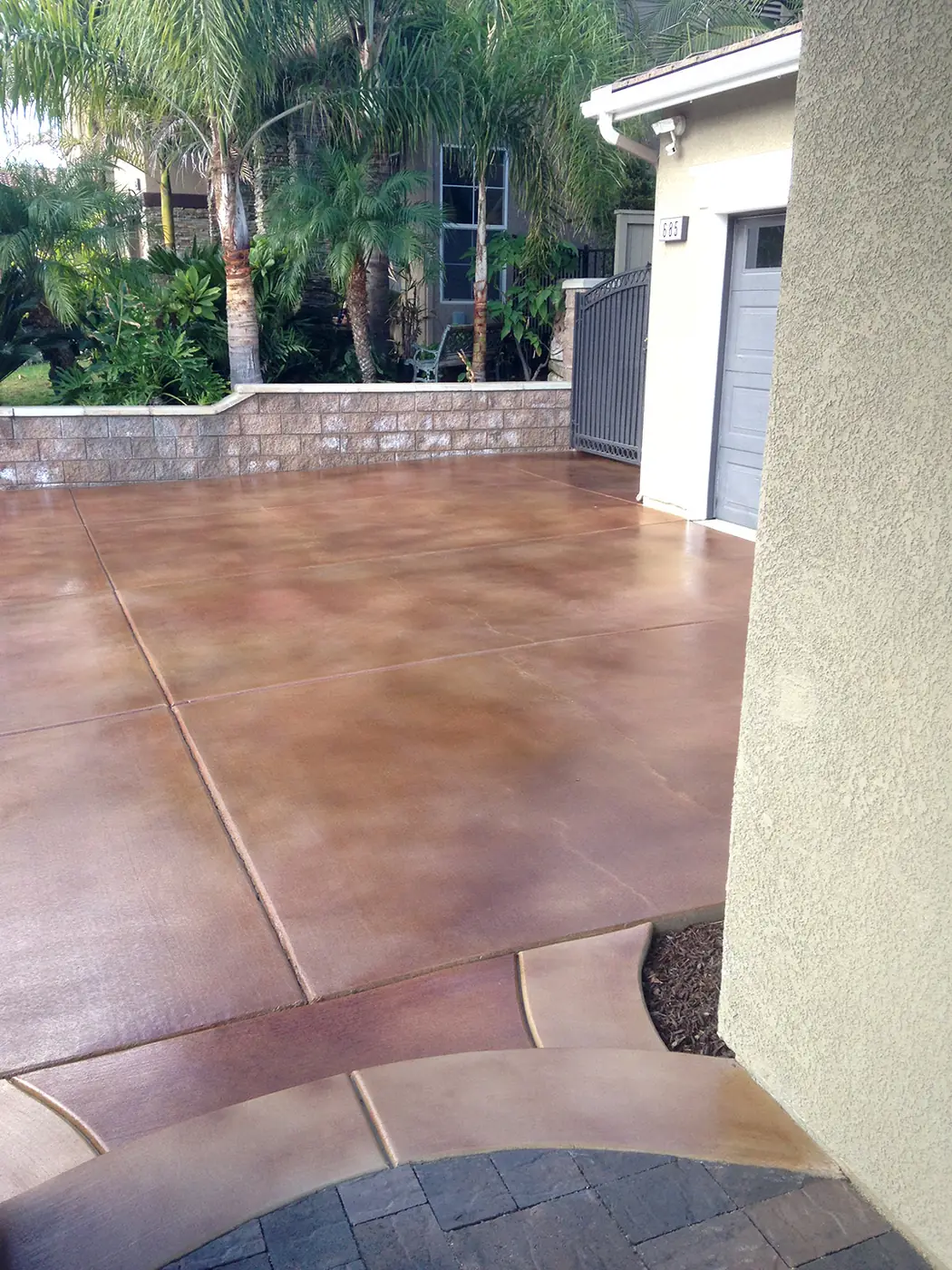 Stained side yard patio with a paver-look border against a rendered wall