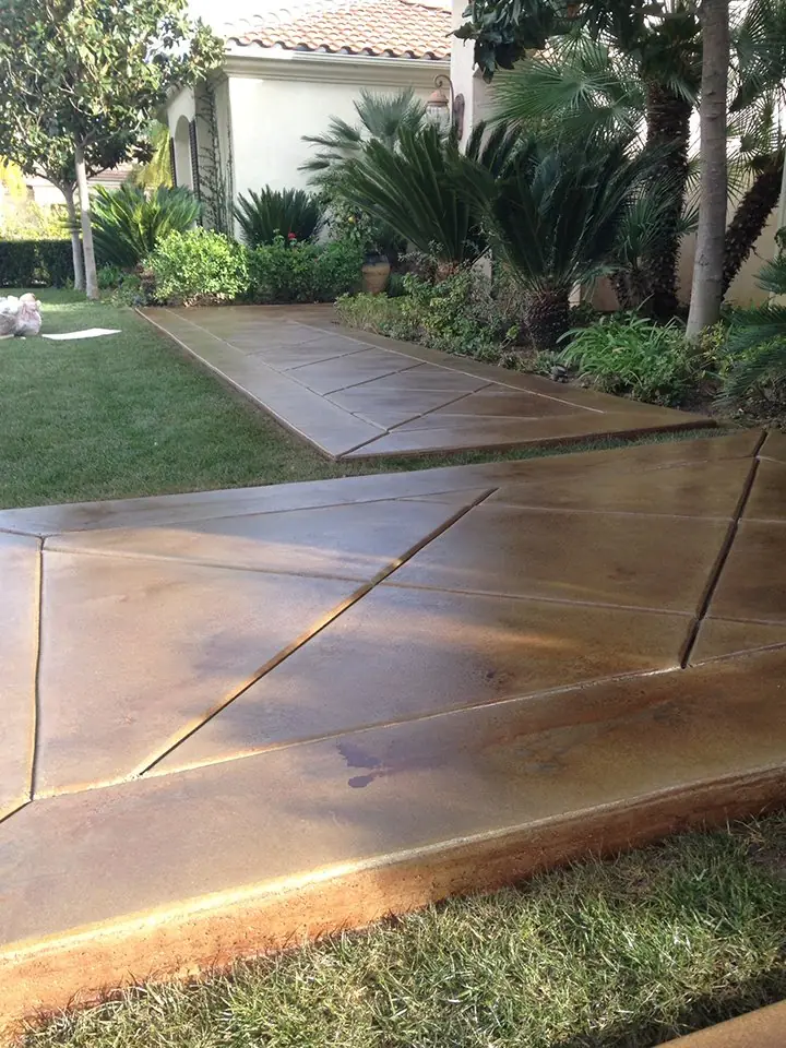Tan stained walkway scored in a diamond pattern beside a lawn