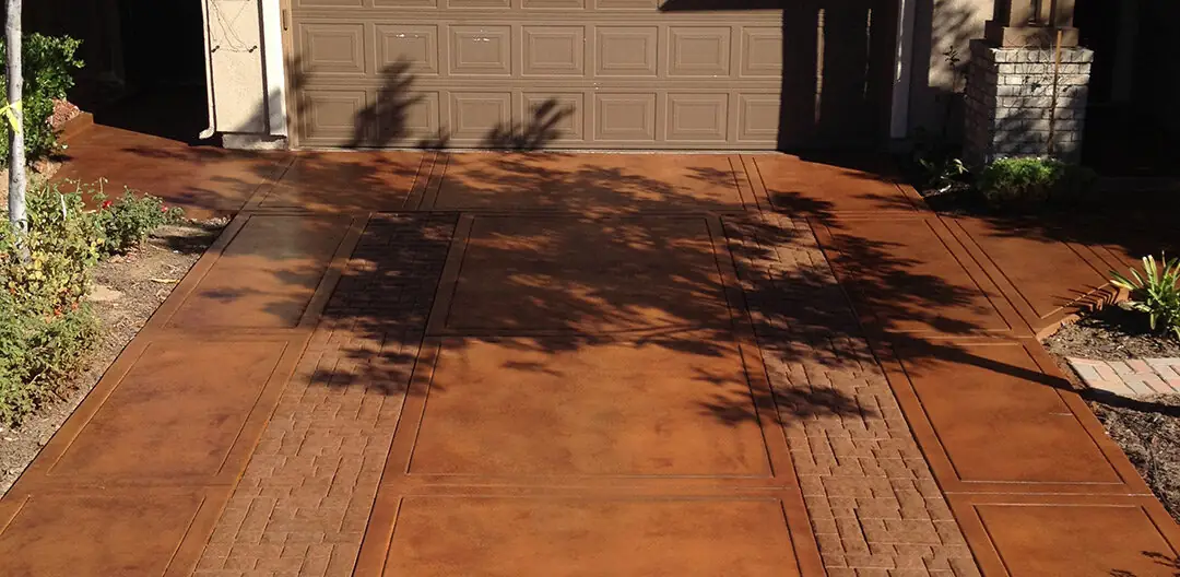 Rust stained patio in a wood-plank pattern beside a garage door