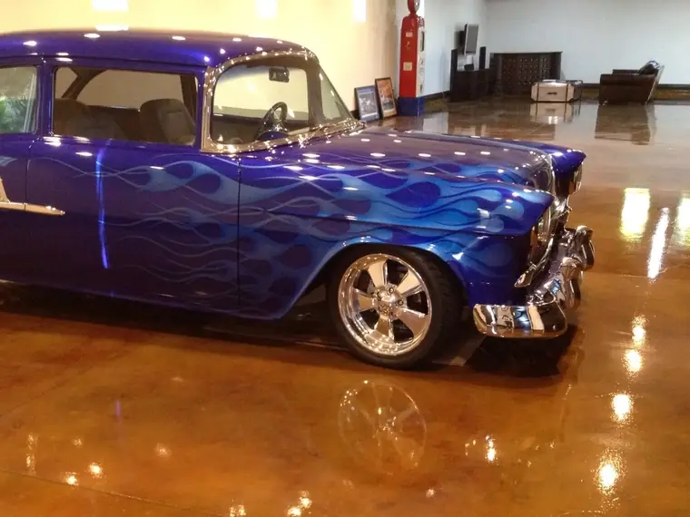 Custom blue flamed hot rod parked on a glossy copper-stained garage floor