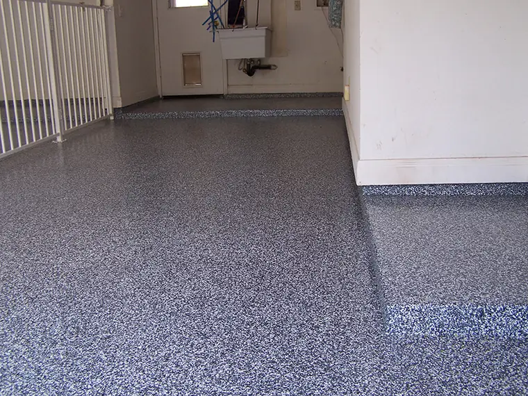 Gray and blue flake epoxy garage floor running up to the door into the house