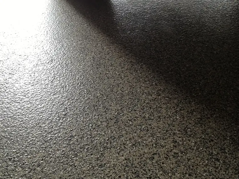 Car tire resting on a gray flake epoxy garage floor