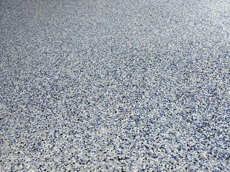 Blue, white and gray flake epoxy floor in a garage still in bare wood framing