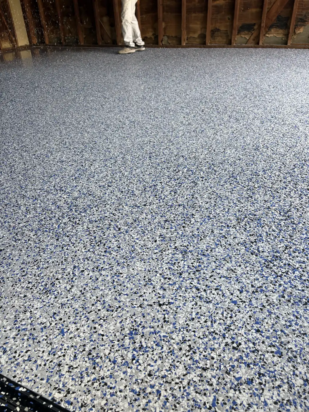 Blue, white and gray flake epoxy floor in a garage still in bare wood framing