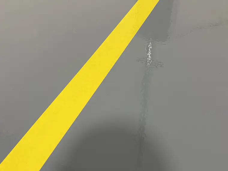 Yellow safety stripe running diagonally across a gray epoxy floor