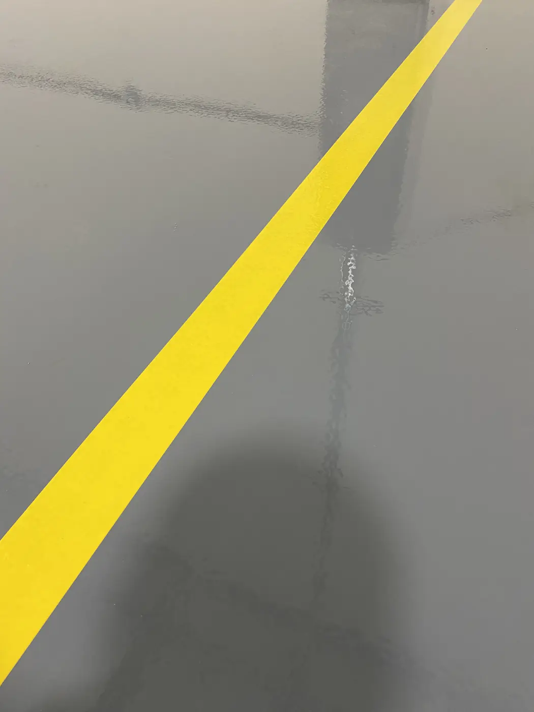 Yellow safety stripe running diagonally across a gray epoxy floor