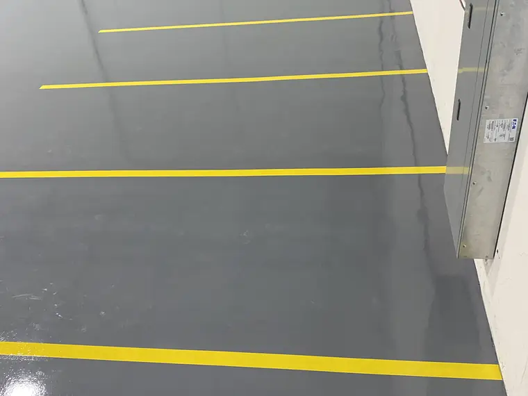 Yellow aisle lines running across a glossy gray epoxy warehouse floor