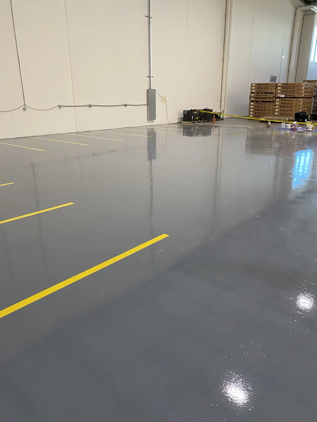 Gray epoxy floor with yellow lines leading toward stacked warehouse pallets