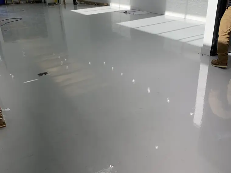 Gray epoxy floor in a bright industrial room with sunlight across it