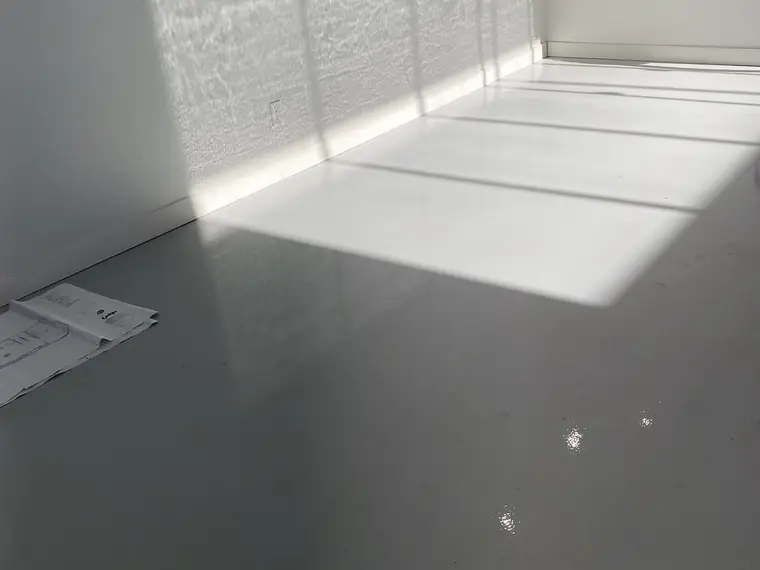 Sunlight falling across a fresh gray epoxy floor in an empty industrial unit