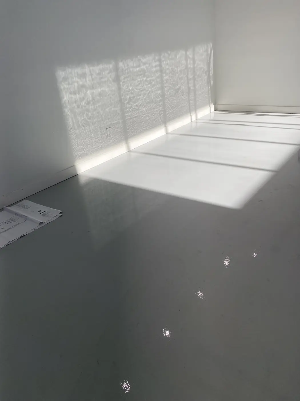 Sunlight falling across a fresh gray epoxy floor in an empty industrial unit