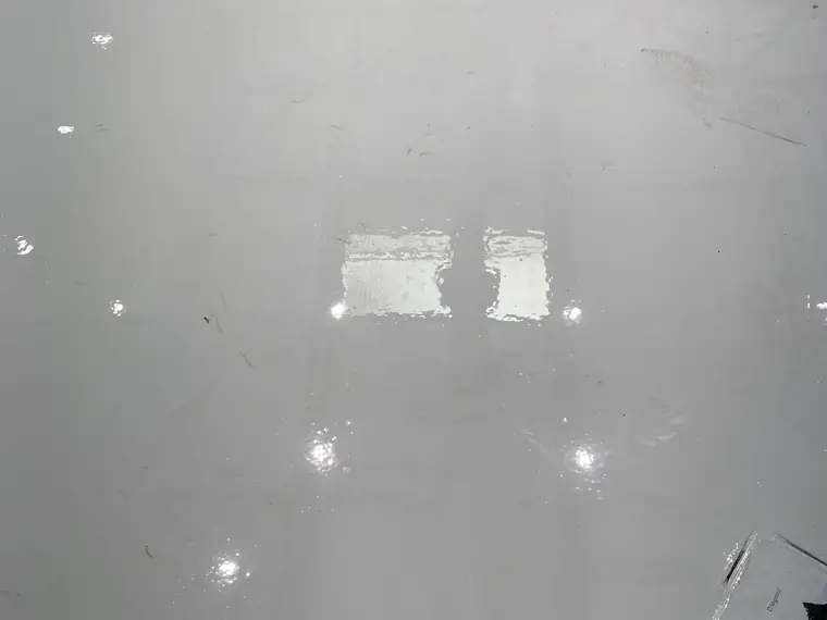 Gray epoxy floor with the old patch lines still visible through the gloss