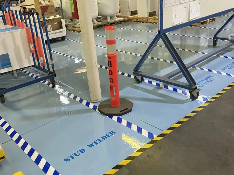 Blue and white striped safety zones marked on a pale blue epoxy plant floor