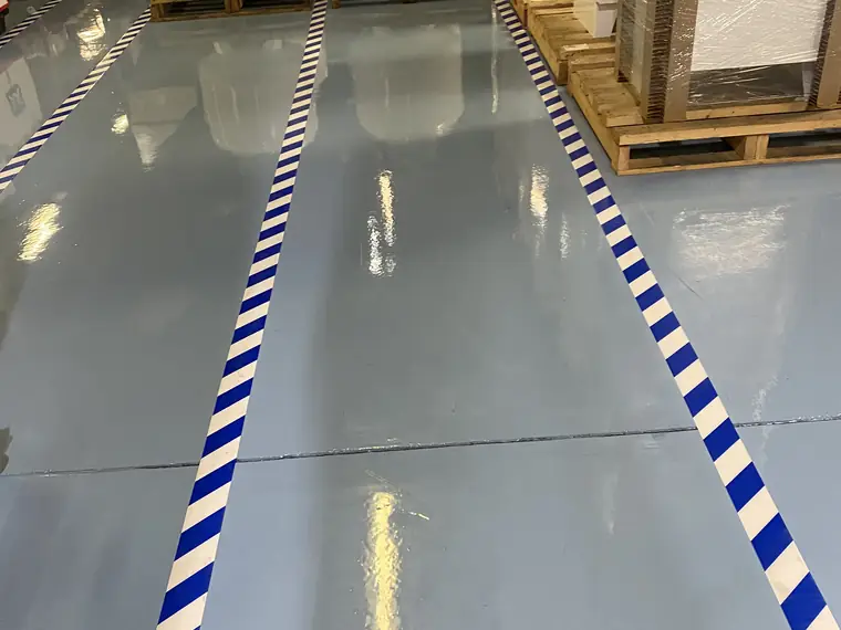 Pale blue epoxy plant floor with blue and white striped walkway lines and a stencilled label