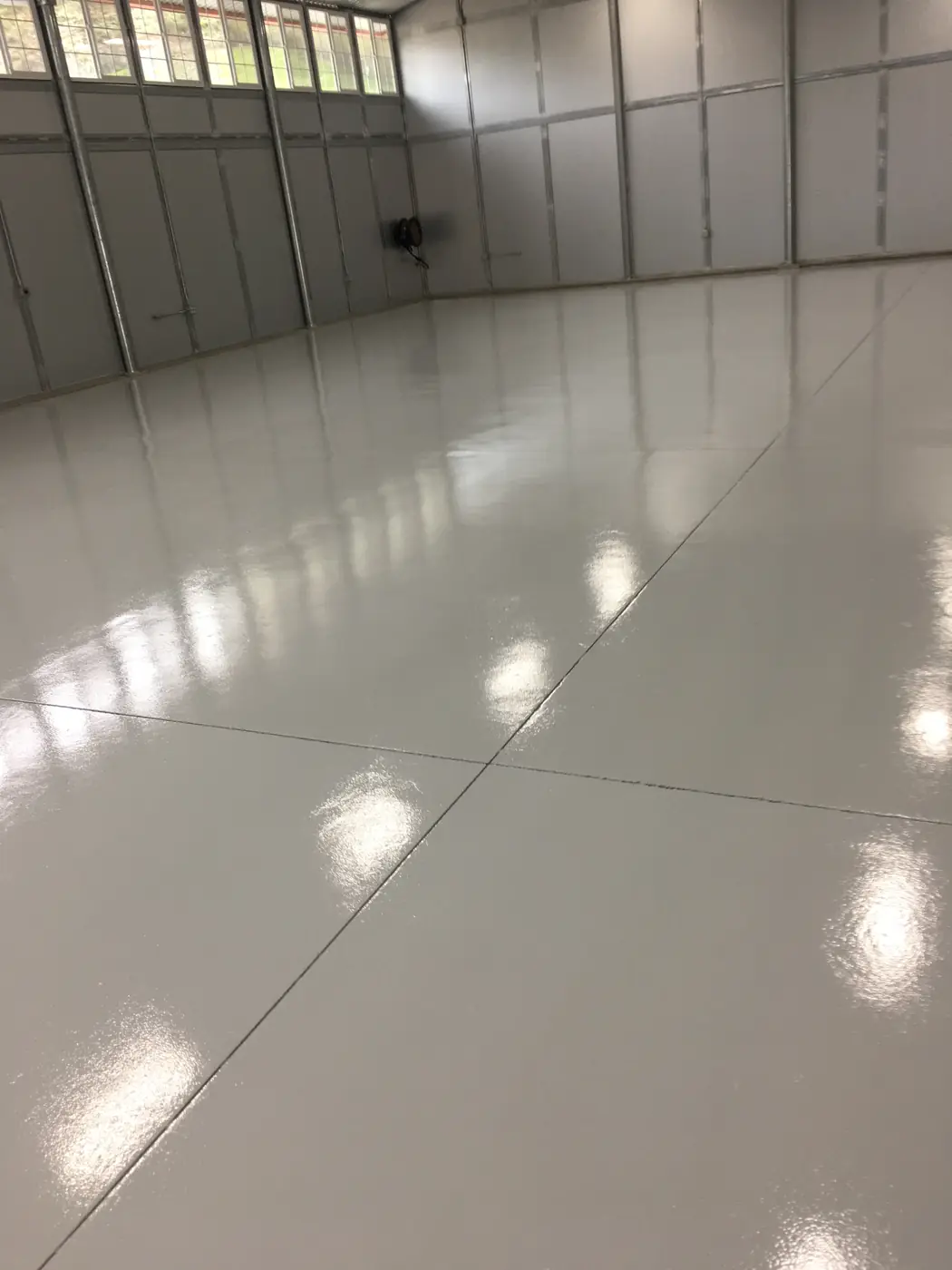 Light gray epoxy floor running the length of a clean warehouse