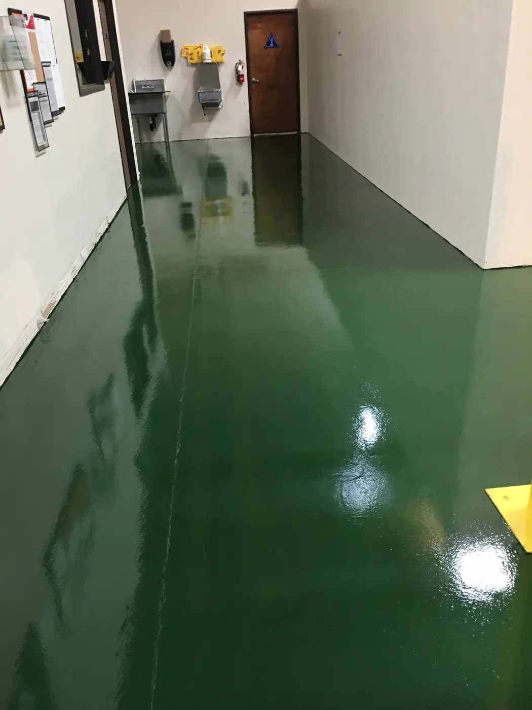 Glossy dark green epoxy corridor between white warehouse walls