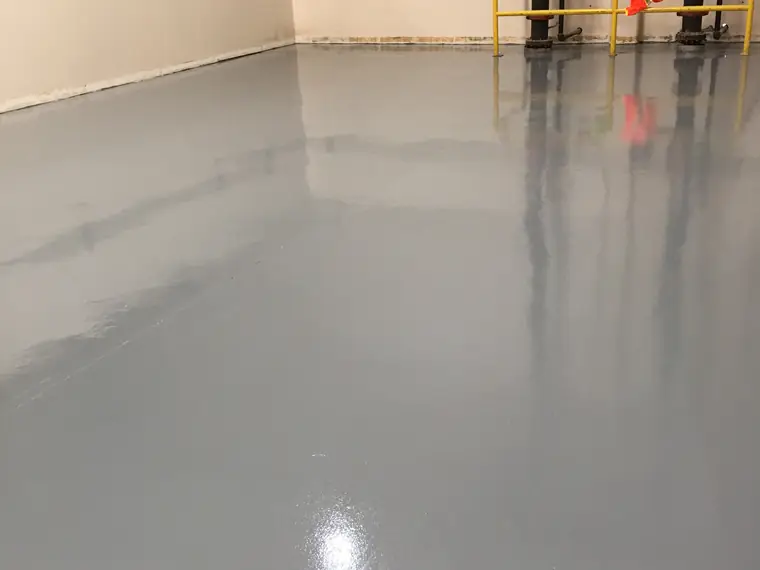 Gray epoxy floor in a warehouse bay with yellow guard rails at the far wall